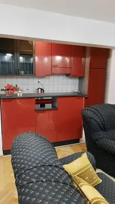 a kitchen with red cabinets and a couch in a room at Nova DOM in Banja Luka