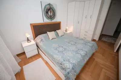 a bedroom with a bed with a blue comforter and pillows at City Museum Apartments Banja Luka in Banja Luka