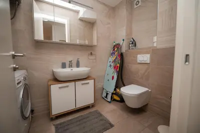a bathroom with a sink and a toilet and a mirror at City Museum Apartments Banja Luka in Banja Luka