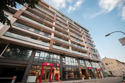 a tall building on a city street with a store at City Museum Apartments Banja Luka in Banja Luka