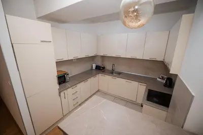 an empty kitchen with white cabinets and a chandelier at City Museum Apartments Banja Luka in Banja Luka