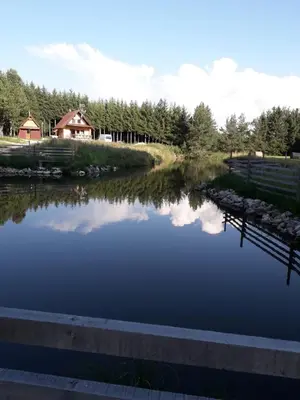 a river with a dock and a house in the background at Dream House in Kupres
