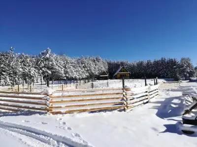 a snow covered field with a fence and trees at Dream House in Kupres