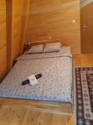 a bed in a room with wooden walls and wood floors at Vikendica Mia in Šipovo