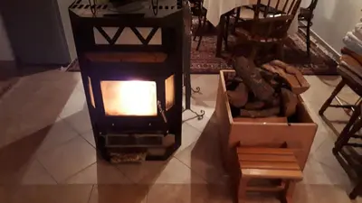 a woodburning stove in a room with a table and chairs at Kuća za odmor VITICA s vanjskim kaminom in Kupres