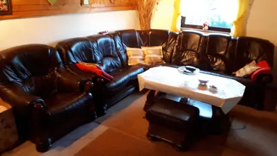 a living room with a leather couch and a table at Kuća za odmor VITICA s vanjskim kaminom in Kupres