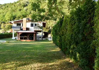 a house with a hedge in front of a yard at Apartmani TIS in Banja Luka