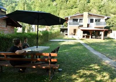 two people sitting on a bench under an umbrella at Apartmani TIS in Banja Luka