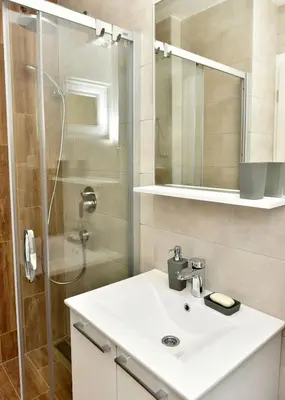 a bathroom with a white sink and a shower at Apartmani TIS in Banja Luka