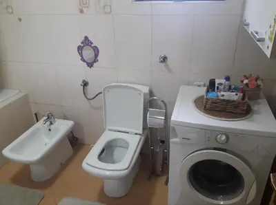 a bathroom with a toilet and a sink and a washing machine at Kuća za odmor La Mia Casa in Doboj