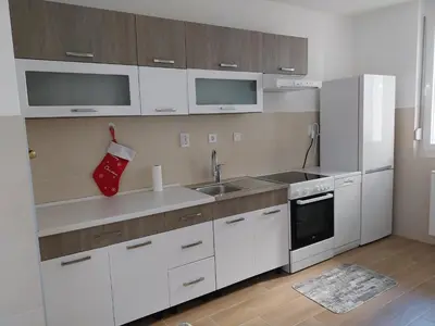 a kitchen with white cabinets and a sink and a refrigerator at Delta Lux Apartment in Banja Luka