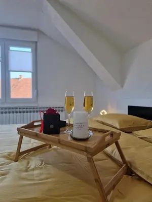 two glasses of wine on a wooden table in a room at Apartments Gradiska in Bosanska Gradiška