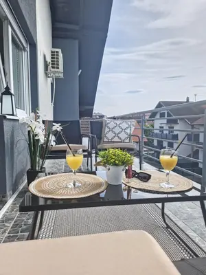 two tables on a balcony with two glasses of orange juice at Apartments Gradiska in Bosanska Gradiška