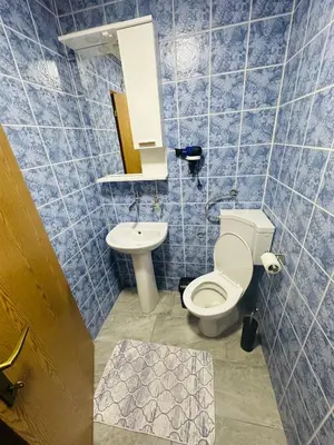 a blue tiled bathroom with a toilet and a sink at Apart Cobras Jajce in Jajce