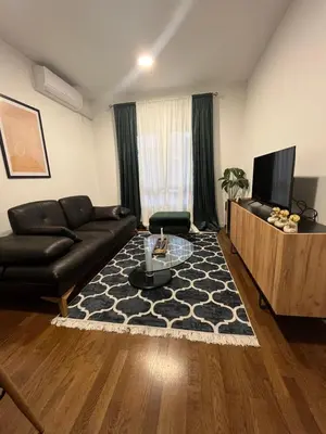 a living room with a black leather couch and a television at Apartman Lux Moli Banja Luka in Banja Luka