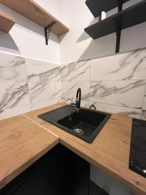 a kitchen with a black sink and marble walls at Apartman Lux Moli Banja Luka in Banja Luka
