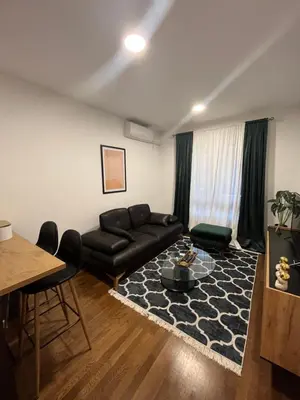 a living room with a black leather couch and a table at Apartman Lux Moli Banja Luka in Banja Luka