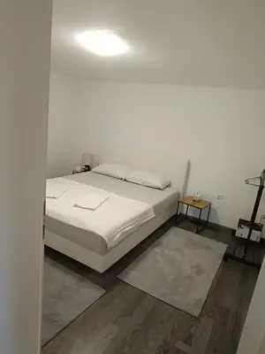 a white bedroom with a bed and a lamp at Apartment Lane in Bihać