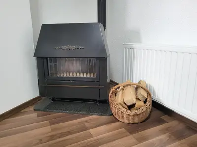 a fireplace sitting on a floor next to a basket at Apartman Studenac in Kiseljak