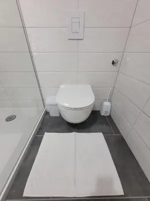 a white bathroom with a toilet and a bath tub at Apartman Studenac in Kiseljak