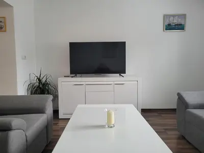 a living room with a tv and a white table at Apartman Studenac in Kiseljak