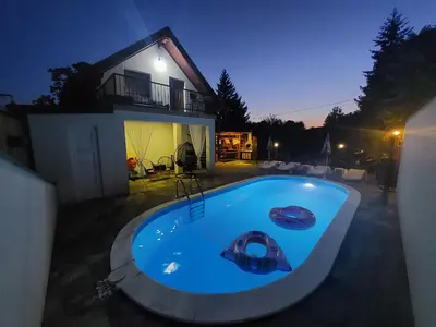 a swimming pool in front of a house at night at La Mia Casa in Bihać