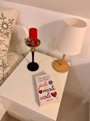 a table with a candle and a book and a lamp at Farmhouse Dzeni in Vlasic