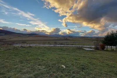 a field with a sky with clouds in a field at Kupres Desktop - mountain house in Kupres