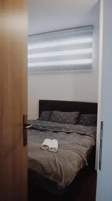 a bedroom with a bed with shoes and a window at Apartman Barbi in Kupres