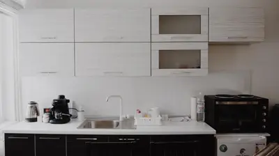 a kitchen with white cabinets and a sink and a microwave at Apartman Barbi in Kupres