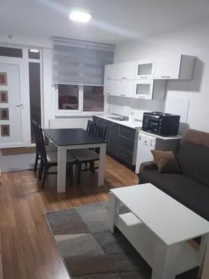 a kitchen and living room with a table and a couch at Apartman Barbi in Kupres