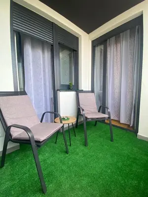 two chairs and a table on a balcony with green grass at Infinity in Banja Luka