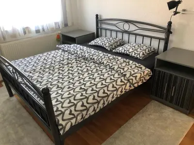 a bed with a black frame and pillows on it at Apartman Cypres in Kupres