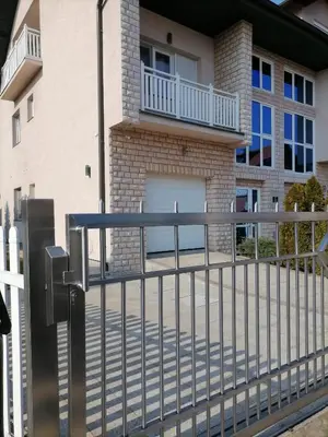 a fence in front of a house with a garage at Apartman MN Teslic in Teslić
