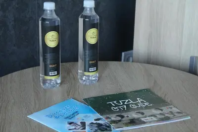two bottles of water on a table with a book at Apartman De Luxe in Tuzla