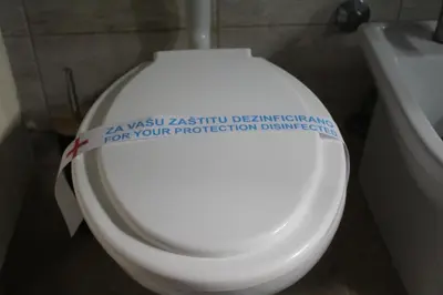 a bathroom with a toilet with a sign on it at Apartman De Luxe in Tuzla