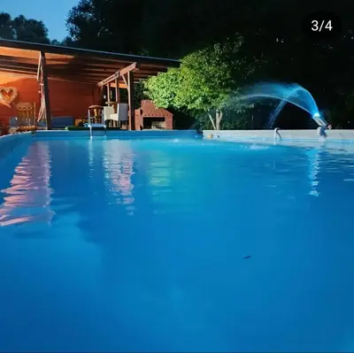 a pool with a water fountain in front of a house at Vikendica Mimiena in Račić