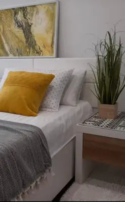 a bed with a yellow pillow and a potted plant at Apartman Jasmina in Bihać