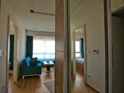 a living room with a blue chair and a room with a bed at Downtown apartment in Banja Luka