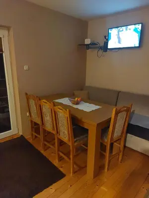 a dining room table with four chairs and a television at Vikendica Grganović in Vlasic
