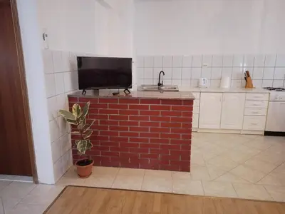a kitchen with a brick counter with a television on it at Barun apartman in Lusnić