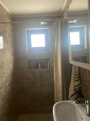 a bathroom with a sink and a shower with a window at Apartman Green in Šišava