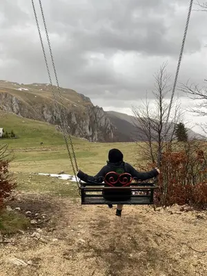 a person is sitting on a swing at Apartman Green in Šišava