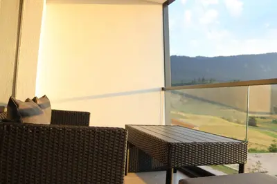 a table and chairs on a balcony with a large window at LUX Apartmani Vlašićka čarolija in Travnik