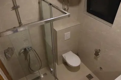 a bathroom with a toilet and a glass shower stall at LUX Apartmani Vlašićka čarolija in Travnik