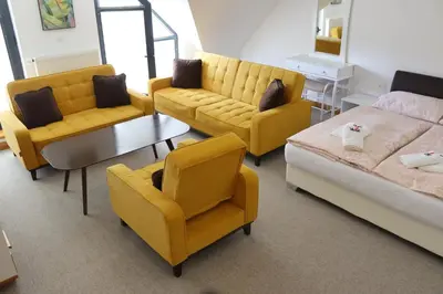 a room with yellow furniture and a bed and a table at Apartmani Vlašić-Petrol in Travnik