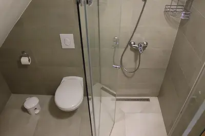 a bathroom with a toilet and a glass shower at Apartmani Vlašić-Petrol in Travnik