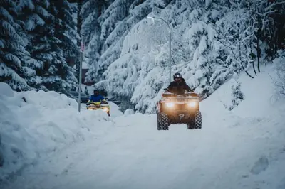 two people on atvs driving down a snow covered road at Apartments Kiki Vlašić in Vlasic