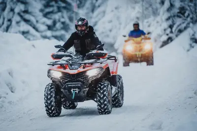 a man on a fourwheeler driving down a snow covered road at Apartments Kiki Vlašić in Vlasic