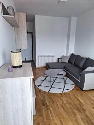 a living room with a black couch and a table at Apartman Mia 2 Banja Luka in Banja Luka